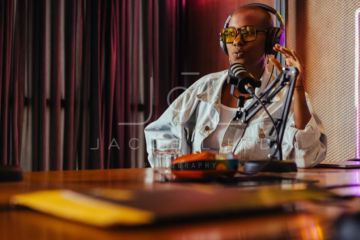 Confident female radio host recording in studio with neon light decor